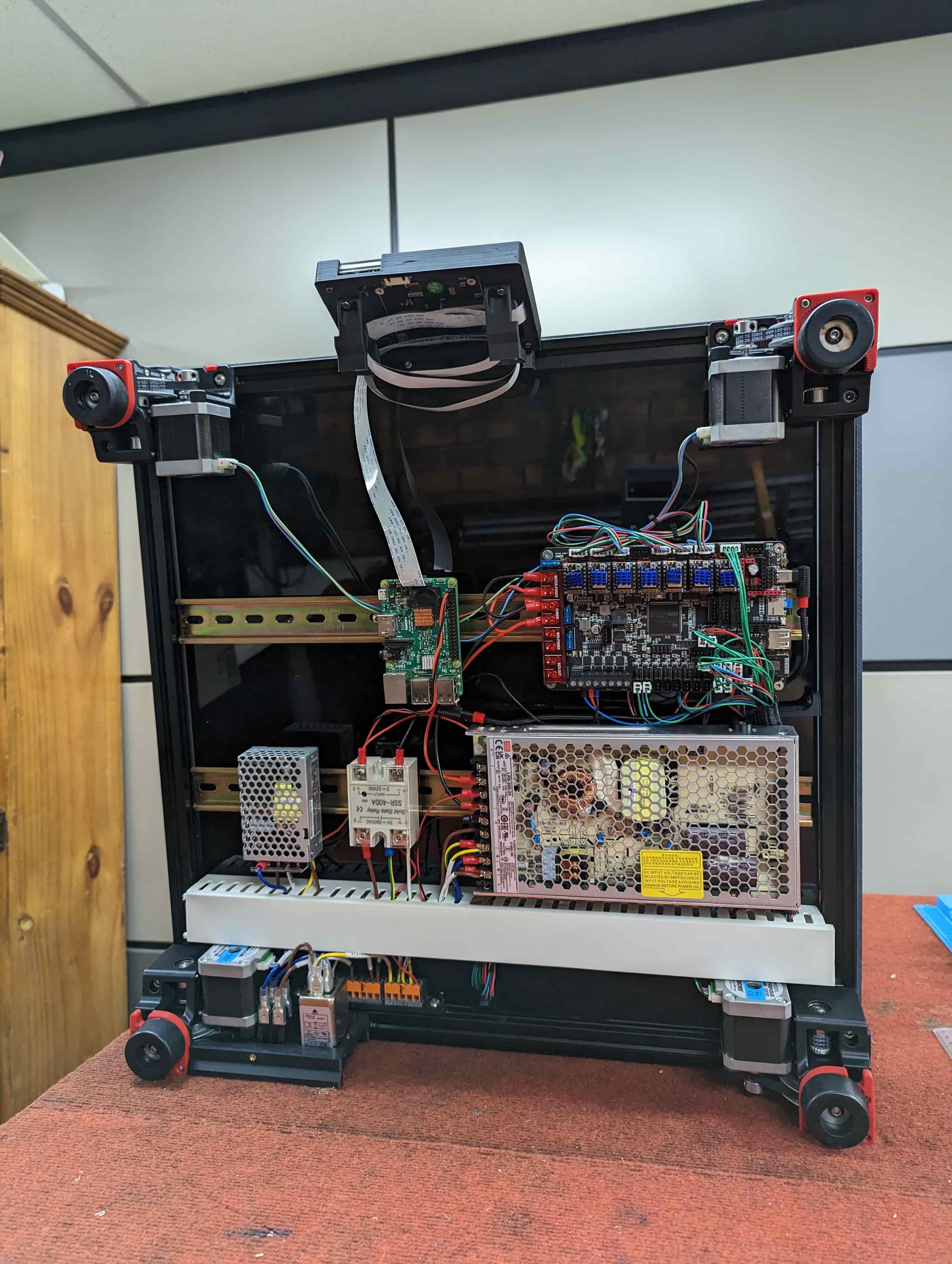 Open rear electronics compartment of a custom enclosed printer showing its controller, computer and power supplies
