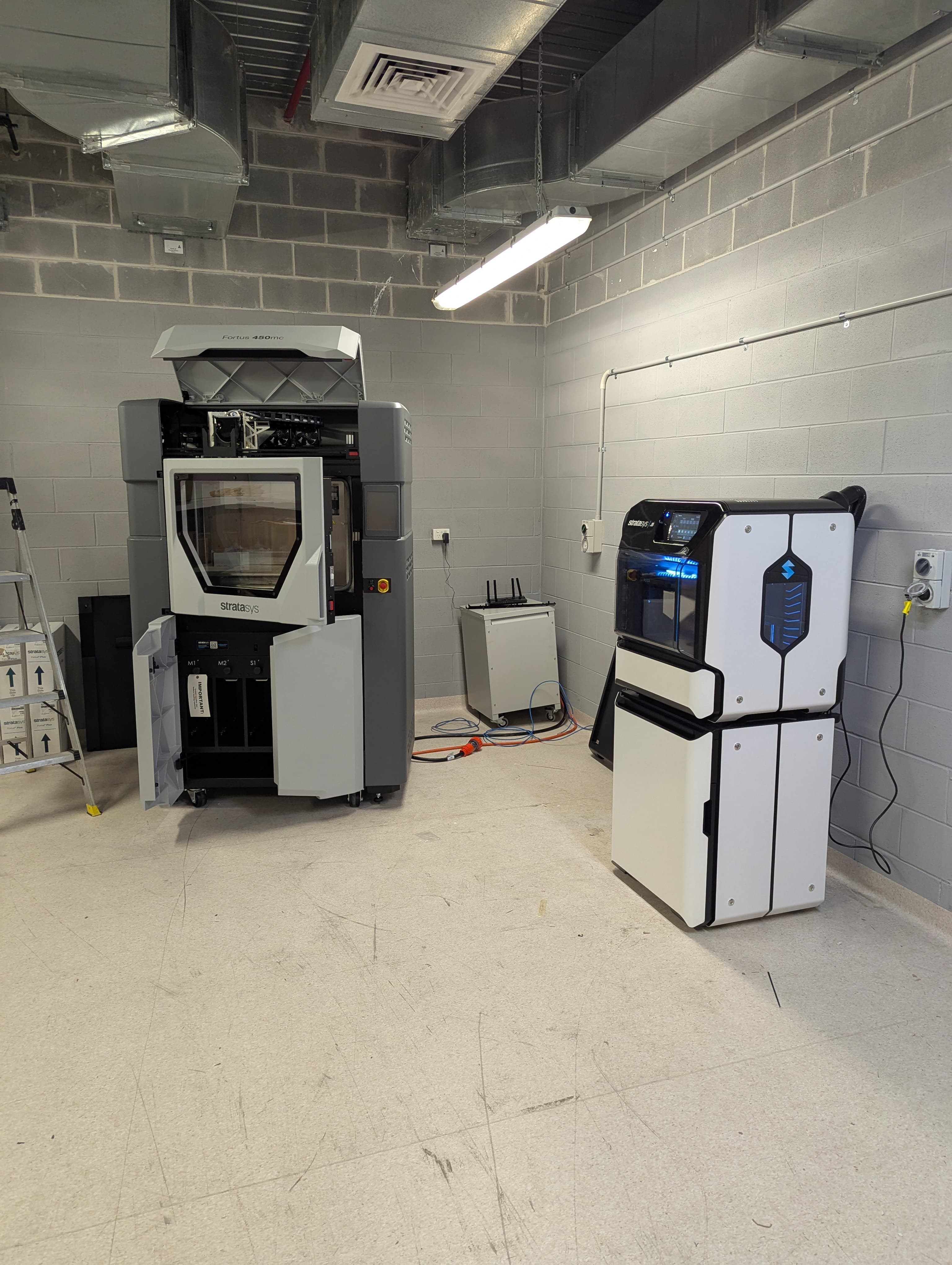 FDM printer producing a full build plate of matching black workshop brackets