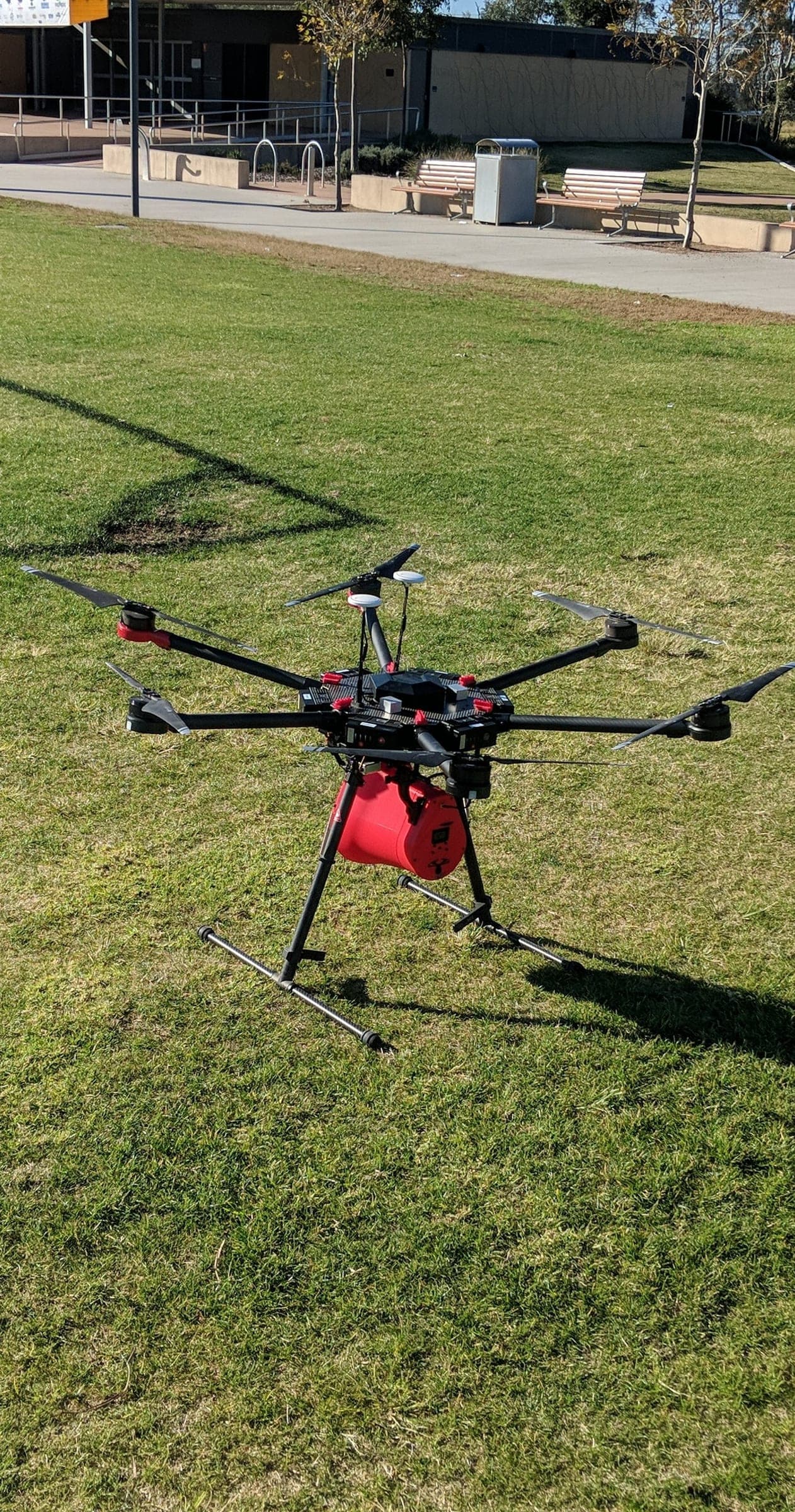 Large multirotor drone carrying a red megaphone payload during an outdoor field test