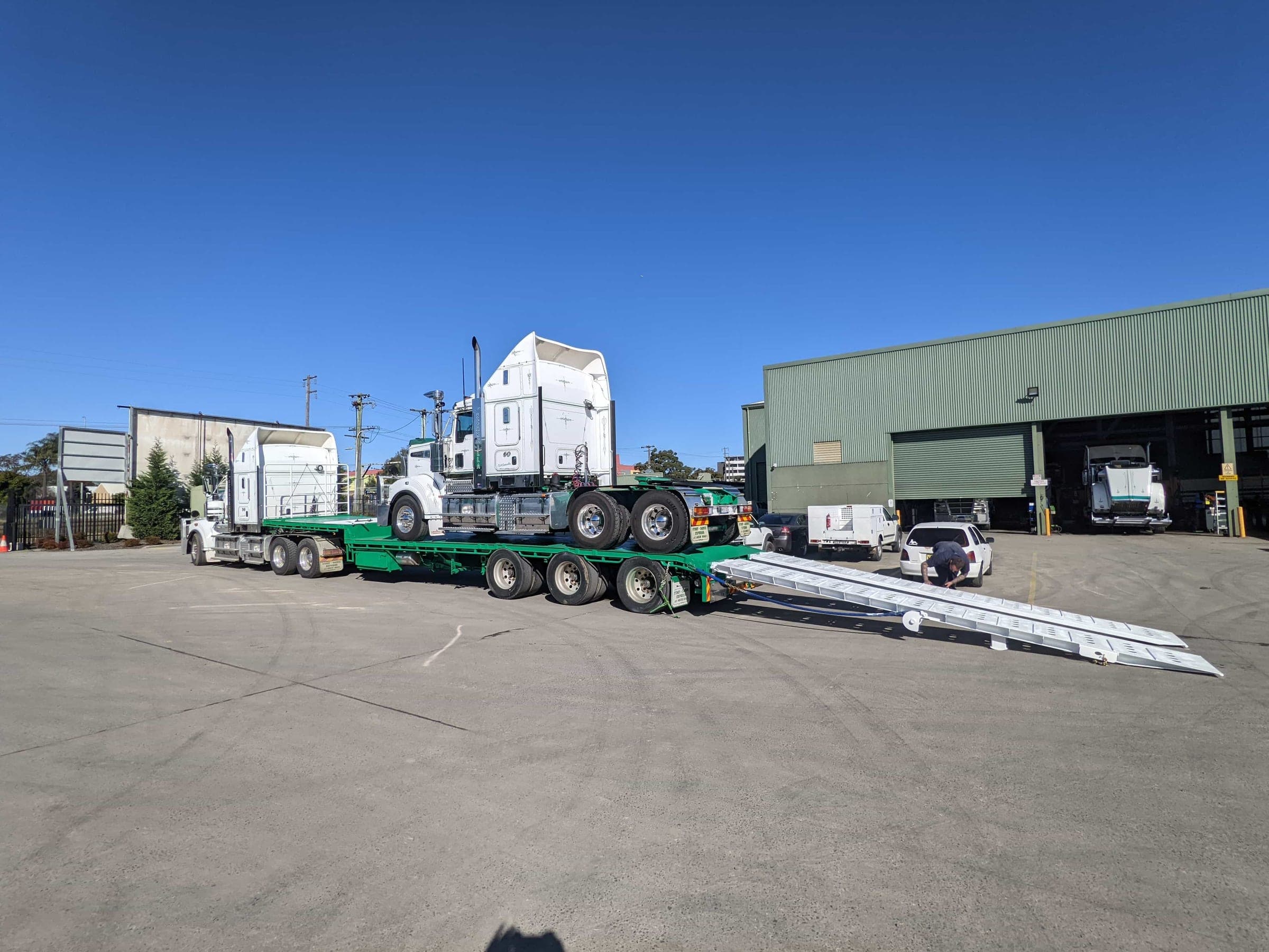 Wide view of a loaded truck on the transport trailer with both ramps lowered